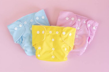 Yeniden kullanılabilir bez bebek bezleriyle yatıyordu. Pastel arka planda çevre dostu bebek bezleri. Sürdürülebilir yaşam tarzı, sıfır atık fikri