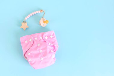 Yeniden kullanılabilir pembe bez bebek bezi ve emzik ile düz yatıyordu. Mavi pastel arka planda çevre dostu bebek bezi. Sürdürülebilir yaşam tarzı, sıfır atık fikri