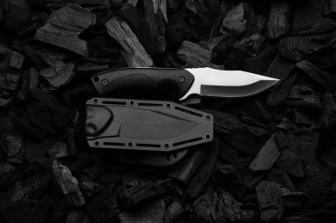 Gümüş bıçaklı ve plastik saplı modern bir bıçak. Plastik kılıf. Koyu kömür arkaplanı.