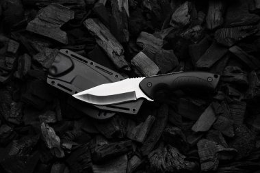 Gümüş bıçaklı ve plastik saplı modern bir bıçak. Plastik kılıf. Koyu kömür arkaplanı.