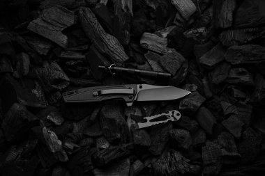 Siyah bıçaklı ve saplı modern çakı. Koyu kömür arkaplanı.