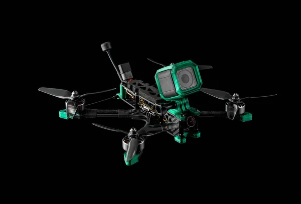 Modern FPV drone. Four-engine aircraft on the radio control. Drone for racing, filming and entertainment. Dark background with a bright green light spot.