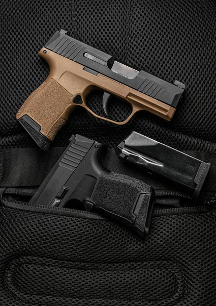 A small modern brown semi-automatic pistols. A short-barreled weapon for self-defense. Arming the police, special units and the army. Dark background.