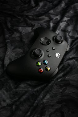 February 22, 2023, Odessa, Ukraine. A black Xbox Wireless Controller. Compatible Xbox Series X|S, Xbox One. Dark camouflage background.
