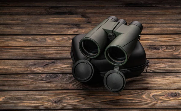 Modern binoculars. An optical instrument for observation at long distances. Dark wooden background.
