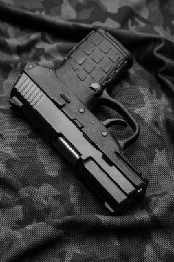 Modern semi-automatic pistol isolate on a camouflage background. Armament for the army and police. Short-barreled weapon.