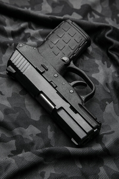 Modern semi-automatic pistol isolate on a camouflage background. Armament for the army and police. Short-barreled weapon.