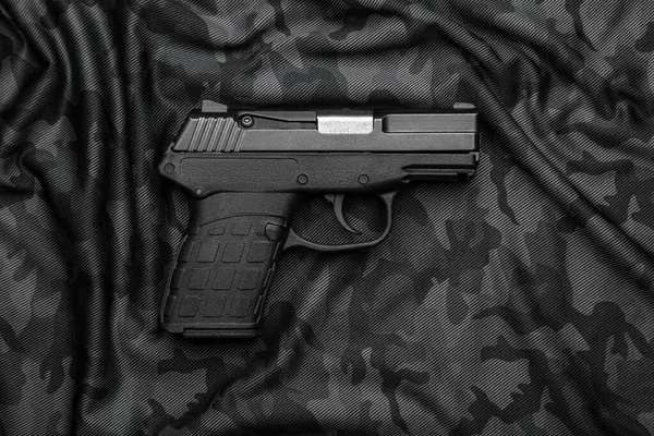 Modern semi-automatic pistol isolate on a camouflage background. Armament for the army and police. Short-barreled weapon.