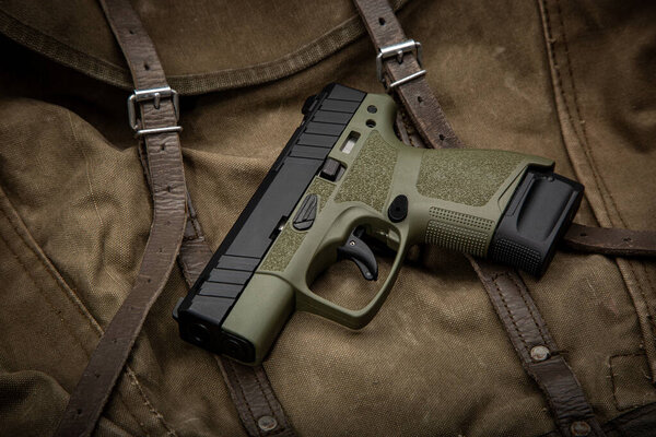 Modern semi-automatic pistol. A short-barreled weapon for self-defense. Arming the police, special units and the army. Vintage canvas background.