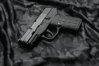 Modern semi-automatic pistol isolate on a camouflage background. Armament for the army and police. Short-barreled weapon.