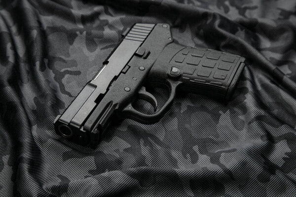 Modern semi-automatic pistol isolate on a camouflage background. Armament for the army and police. Short-barreled weapon.