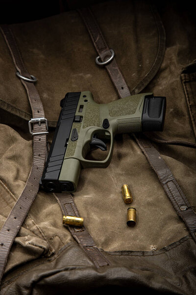 Modern semi-automatic pistol. A short-barreled weapon for self-defense. Arming the police, special units and the army. Vintage canvas background.
