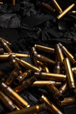 Silahlardan çıkan boş mermiler için yanan siyah kömürler. Savaşın sonuçları işte. Koyu arkaplan.