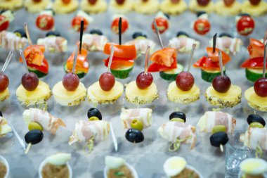 Bir cam masanın üzerine çeşitli aperatifler ve kanepeler serilmiştir. Kaba bir şekilde tasarlanmış ve hazırlanmış yiyecekler. Tatil yemekleri. Hafif arkaplan.