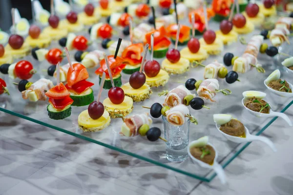 stock image A variety of snacks and canapes are laid out on a glass table. Wickedly designed and laid out food. Holiday catering. Light background.