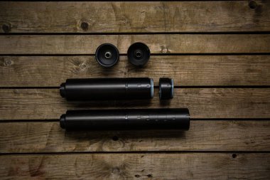 Silahlar için siyah susturucu. Susturucu, saldırı tüfeğinin ucundaydı. Silahlar için modüler susturucular. Klasik ahşap arkaplan.