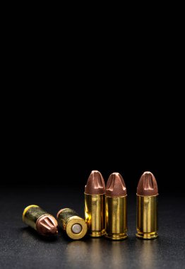 Pistol fişekleri 9 mm 'lik pürüzsüz, parlak bir yüzeyde yansımaları var. Koyu arkaplanda tabancalar ve PCC karabinalar için mühimmat.