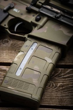 Optik görüşü ve susturucusu olan modern bir karabina. Kamuflaj boyalı silahlar. Eski tahta arkaplan.