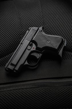 Arka planda küçük yarı otomatik bir tabanca. Silah taşıma ve nefsi müdafaa için. Kısa namlulu silah. Bayanlar tabancası.
