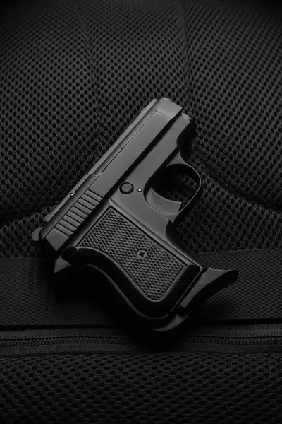 A small semi-automatic pistol on a dark background. Weapons for concealed carry and self-defense. Short-barreled weapon. Ladies pistol.