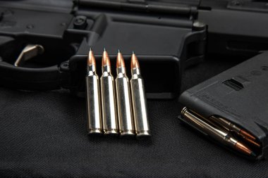 .223 'lük karabina mermilerine yakın çekim. Dolu şarjör. Silahlar arka planda.