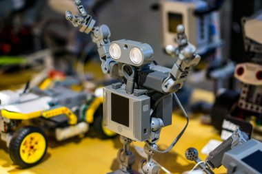 Arkaplanda bulanık robotik parçaları olan, inşaat bloklarından inşa edilmiş oyuncak bir insansı robotun detaylı görüntüsü.