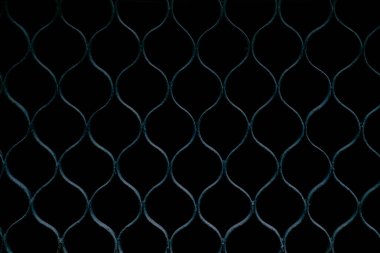 Tekrarlayan elmas desenli, koyu arkaplan, simetrik tasarım, endüstriyel doku, arka plan veya mimari temalar için uygun metal bir çitin yakın çekimi.