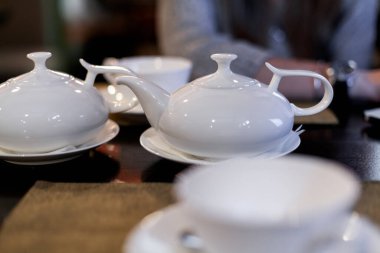 Zarif beyaz porselen çaydanlık ve şeker kasesi, çay için hazırlanmış, arka planı bulanık, hoş ve davetkar bir atmosfer yaratıyor..