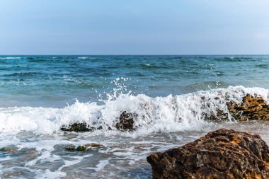 Güneşli bir günde kayalara çarpan okyanus dalgalarının çarpıcı görüntüsü denizin dinamik hareketini ve enerjisini yakalıyor..