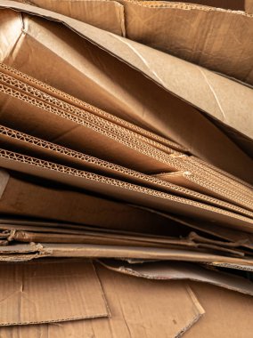 Yığılmış bükülmüş karton katmanların yakın görüntüsü, karmaşık dalga yapısı ve dokusunu sergiliyor, ambalaj, geri dönüşüm, endüstri ve malzeme tasarımı gibi kavramlar için ideal.
