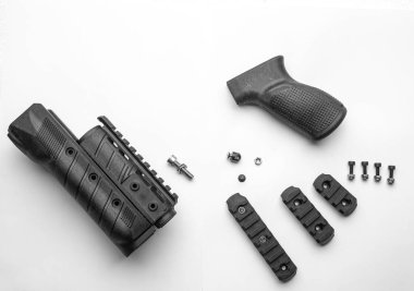 Parts of a firearm accessory, including a handguard, grip, screws, and rail sections, laid out on a white background, highlighting the components and their arrangement. clipart