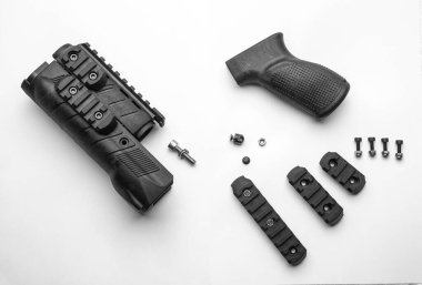 Parts of a firearm accessory, including a handguard, grip, screws, and rail sections, laid out on a white background, highlighting the components and their arrangement. clipart