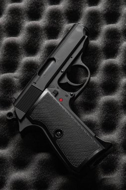 A realistic air pistol, resembling an original firearm, is placed on a textured foam background, showcasing its detailed design and craftsmanship. clipart