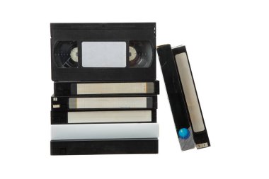 Beyaz arkaplanda eski VHS kasetleri yığını, etiketli ve renkli tasarımlı retro video kasetleri koleksiyonu.