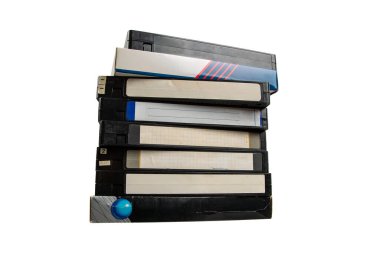 Çeşitli etiketlere sahip sekiz dikey VHS kaset yığını, bazıları el yazısı ve yıpranmış, sade bir arka planda izole edilmiş, analog video formatları ve ev eğlencesi için nostalji uyandırıyor..