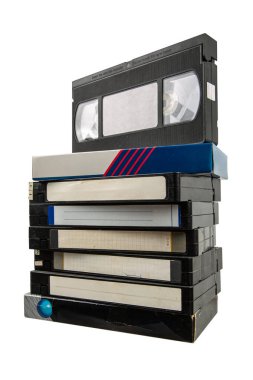 Çeşitli etiketli dokuz VHS kaset yığını, bazıları el yazısı ve yıpranmış, üst bant çantasından biraz çıkarılmış, sade bir arka planda izole edilmiş, analog video biçimleri için nostalji çağrıştırıyor..