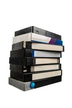 Yıpranmış etiketleri ve davaları beyaz arka planda izole edilmiş uzun bir VHS video kaseti yığını..
