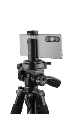 Siyah bir tripoda monte edilmiş, beyaz üzerine izole edilmiş üç kameralı gümüş bir akıllı telefon..