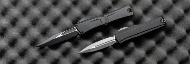 İki taktik otomatik bıçak desenli bir köpük yüzeyde duruyor..