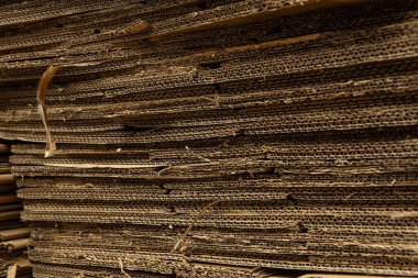 Büyük bir karton yığınının yatay yakın çekimi pürüzlü dokuyu ve sıkıştırılmış katmanları gösterir..