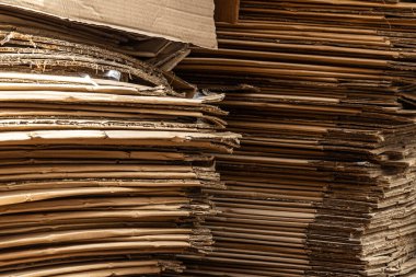 Sıkıştırılmış katmanları ve ham kenarları gösteren büyük bir karton kutu yığınının dikey yakın çekimi.