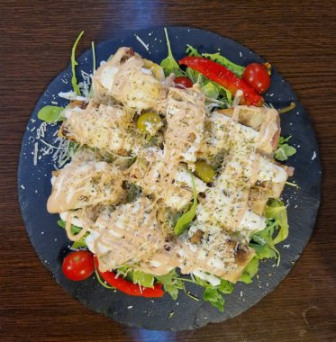 Salam sosisi, zeytin, pepperoni ve mozzarella peyniri ile doldurulmuş lezzetli pizza stromboli rulosu. Masanın üzerindeki granit levhaya yakın plan. Yukarıdan yatay üst görünüm