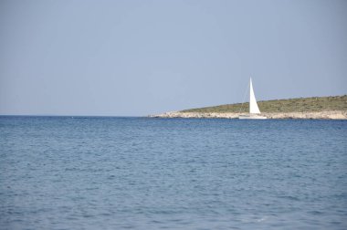Adriyatik Denizi 'nde yelkenli tekne, Hırvatistan' ın Mali Losinj kenti yakınlarında küçük ada ve ufuk çizgisi.