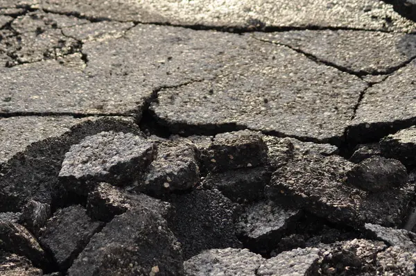 Asfalt yol yüzeyi yığını. Hasarlı asfaltla kaplı tehlikeli bir yol. Kanalizasyonun onarımı veya kazası kavramı. Çatlak asfalt, kuru dönem.
