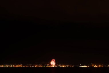 Büyük şehirde havai fişekler ve havai fişekler. Körfezin diğer tarafına bak.