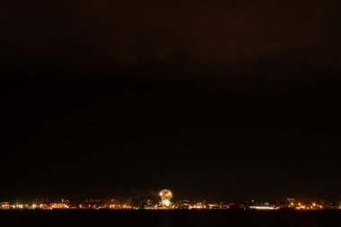 Büyük şehirde havai fişekler ve havai fişekler. Körfezin diğer tarafına bak.