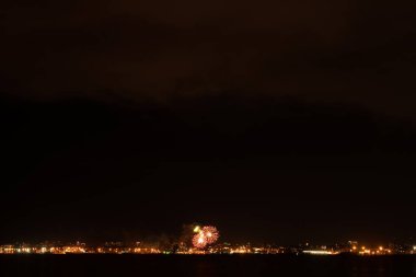 Büyük şehirde havai fişekler ve havai fişekler. Körfezin diğer tarafına bak.