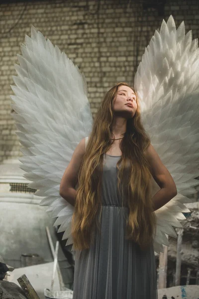 天使の翼を持つ少女が建築の工房に立っている 太陽を見て 後ろの手 — ストック写真