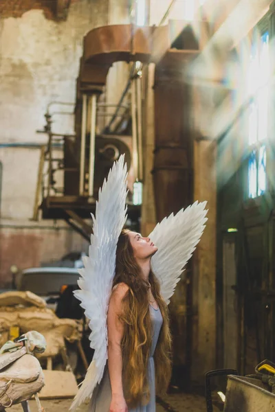 天使の翼を持つ少女が建築家のスタジオに立って頭を上げている 創造的な混乱 — ストック写真