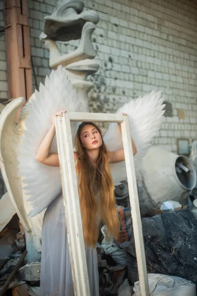 建築遺産 天使をイメージした少女が建築を背景に工房に立ち 白い枠を手にしている — ストック写真